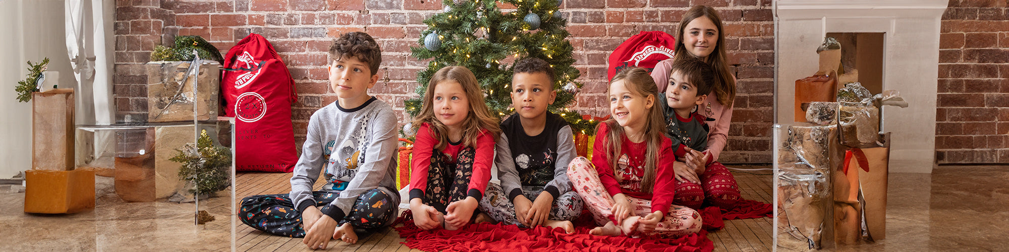 Des enfants devant l'arbre de noel avec des pyjams de noel et du temps des fêtes