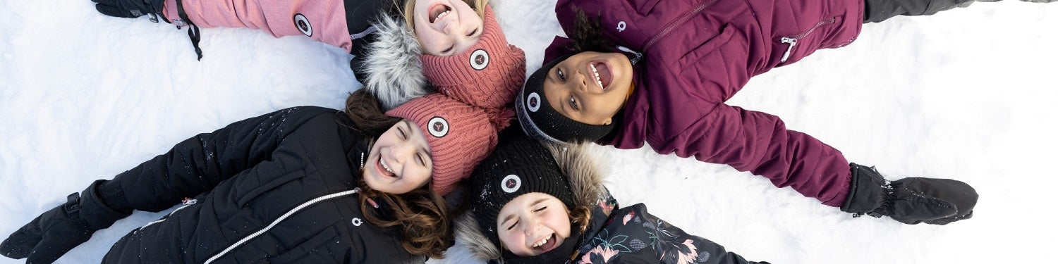 jeune groupe d'enfant fille couché dans la neige avec des tuques rose et noir et manteau d'hiver