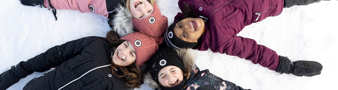 jeune groupe d'enfant fille couché dans la neige avec des tuques rose et noir et manteau d'hiver